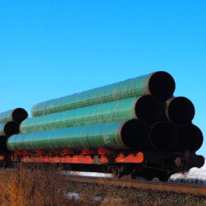 Railway flatcar loaded with large diameter pipe destined for use on the Trans Mountain Pipeline in Western Canada