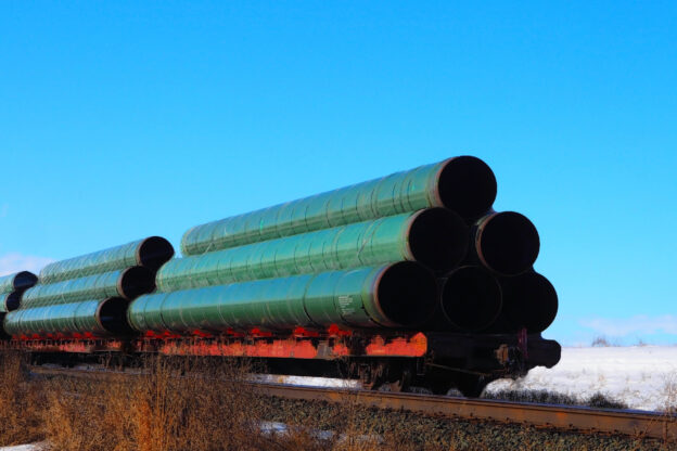 Railway flatcar loaded with large diameter pipe destined for use on the Trans Mountain Pipeline in Western Canada